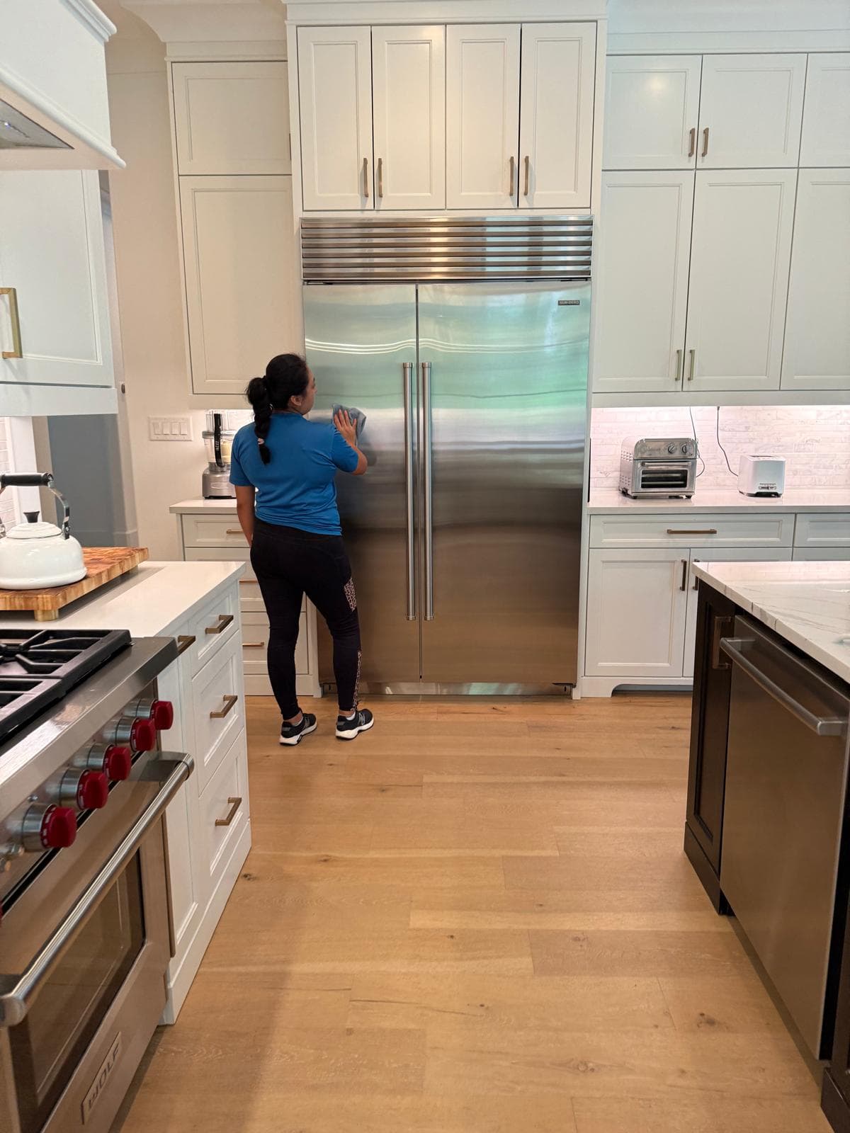 Team member cleaning a stainless steel refrigerator