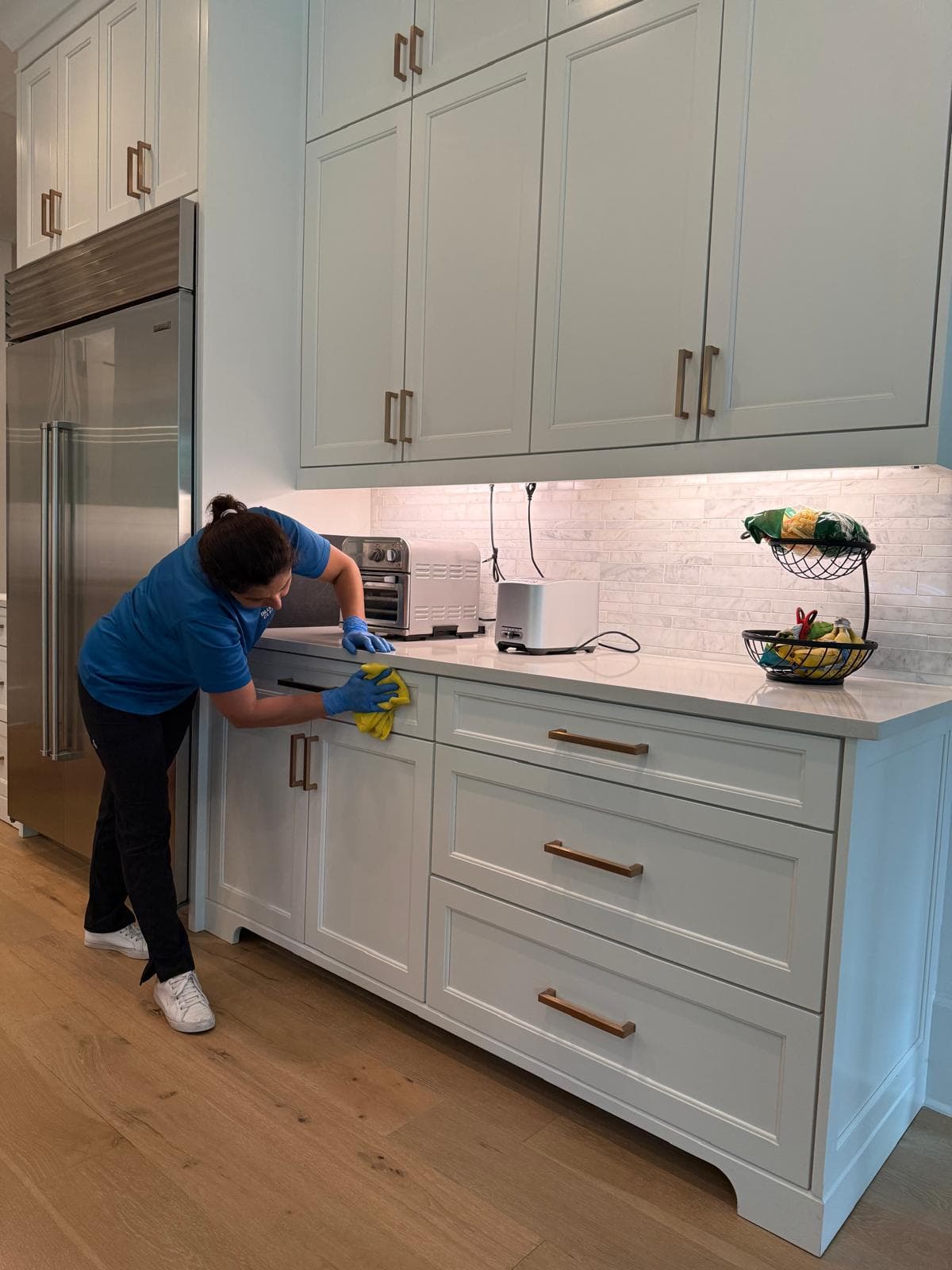 Valeria wiping kitchen cabinet fronts