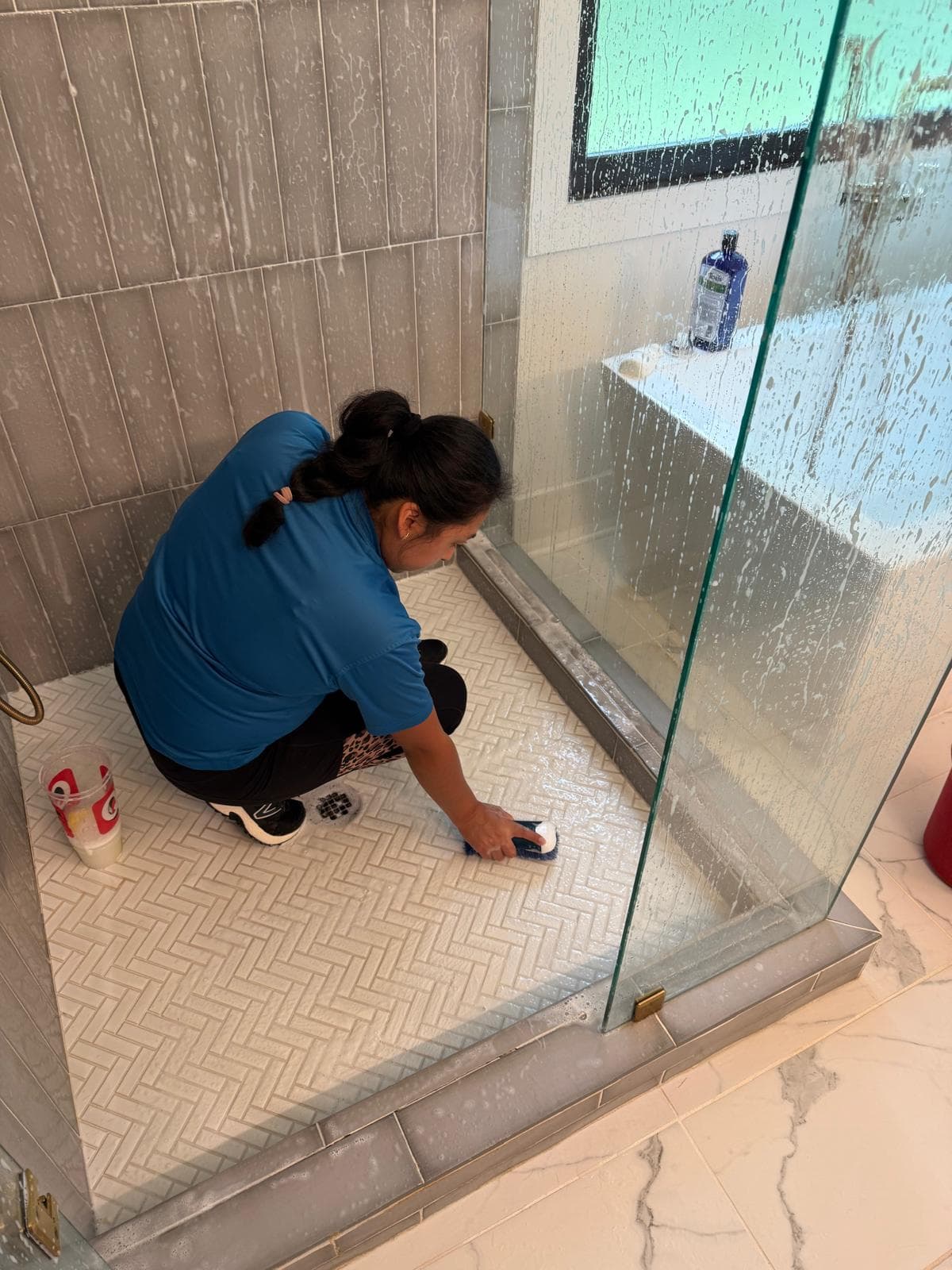 Valeria scrubbing a herringbone tile shower floor
